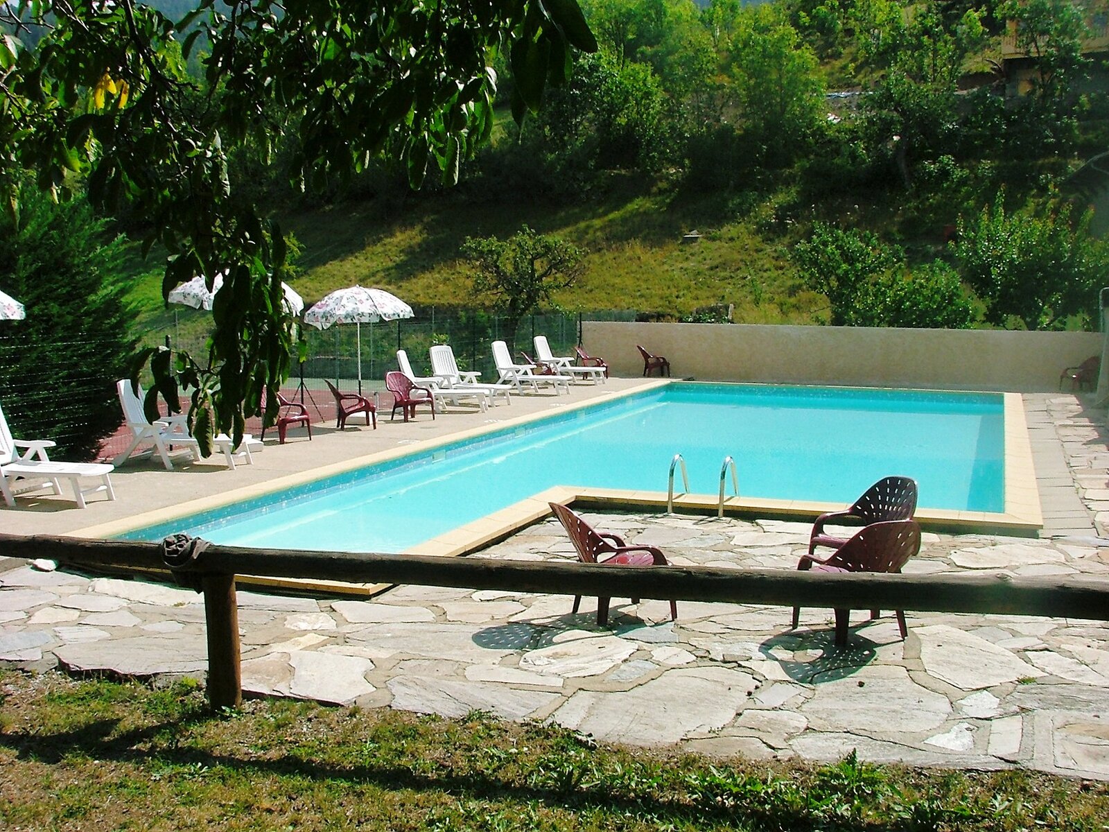 Piscine extérieure de l'auberge Le Rochasson — transats et parasols sous le soleil des Hautes-Alpes